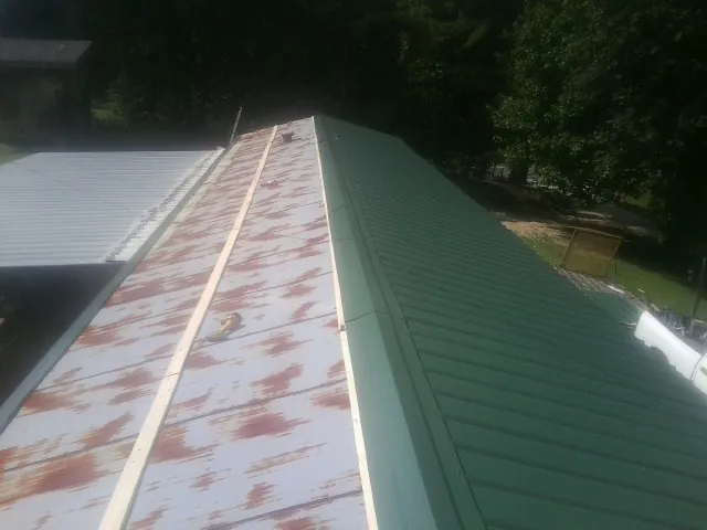 Old rusted panels beside newly installed green metal roofing — Wind Damage Roof Repair by Roofing Brothers in West Plains
