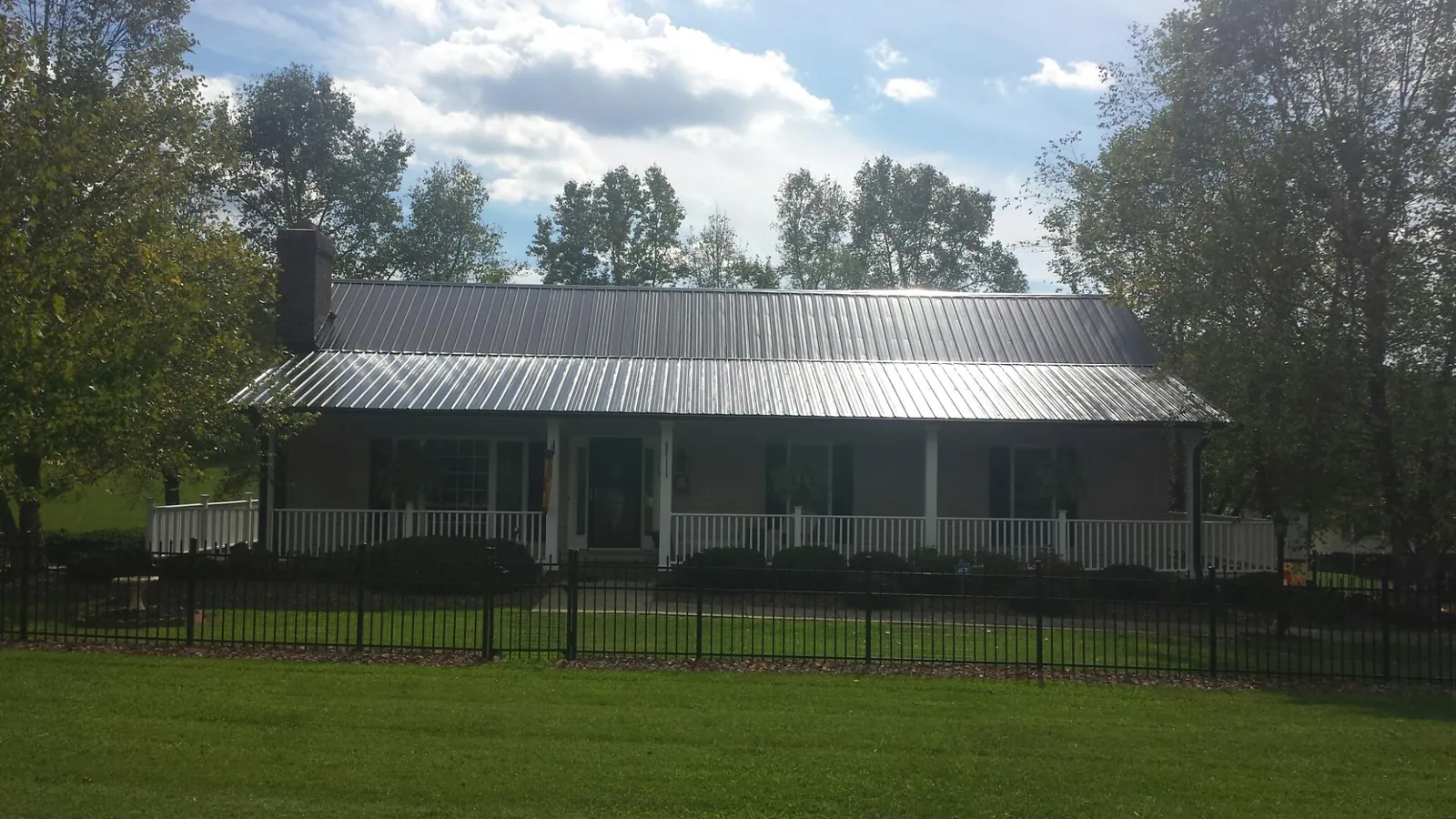Gray metal roof on a brick ranch with a full width front porch — Gutter Guard Installation work by our crew in West Plains