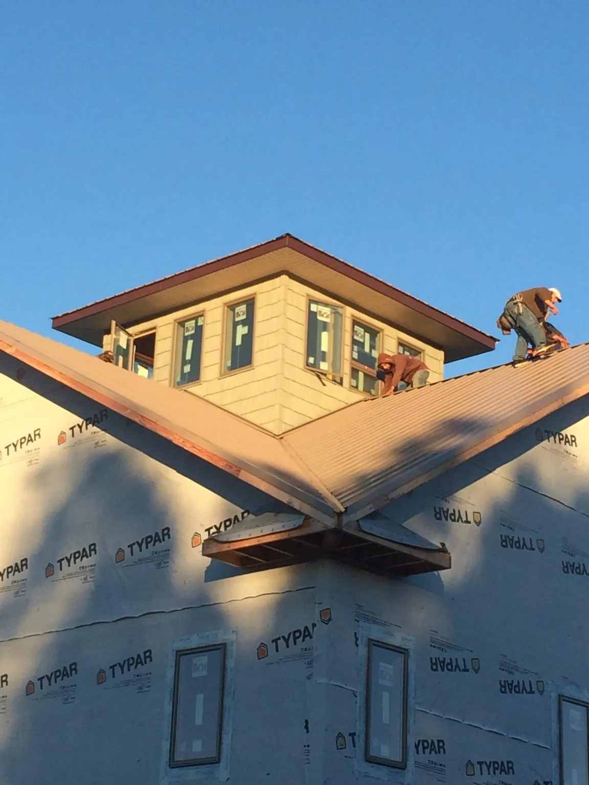 Roofers working around a rooftop cupola on a new metal roof at sunset — Roof Waterproofing in West Plains by Roofing Brothers
